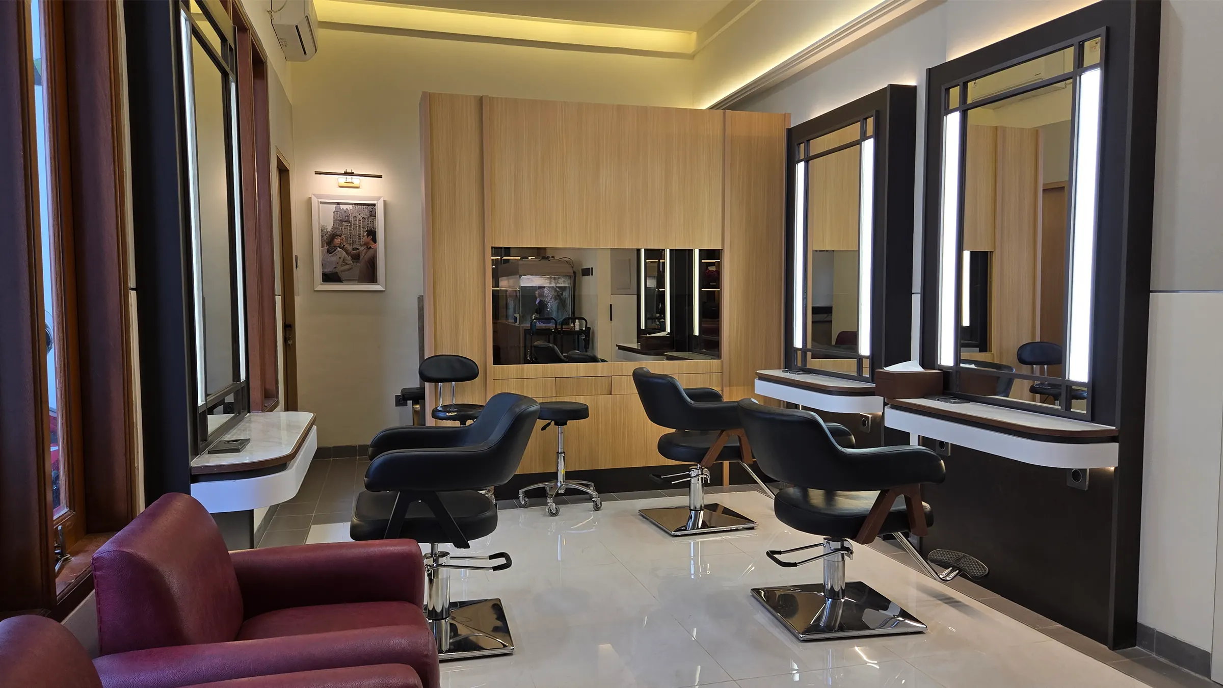 Inside Ganda Hair Studio: three black styling chairs, lit mirrors and warm wood panels