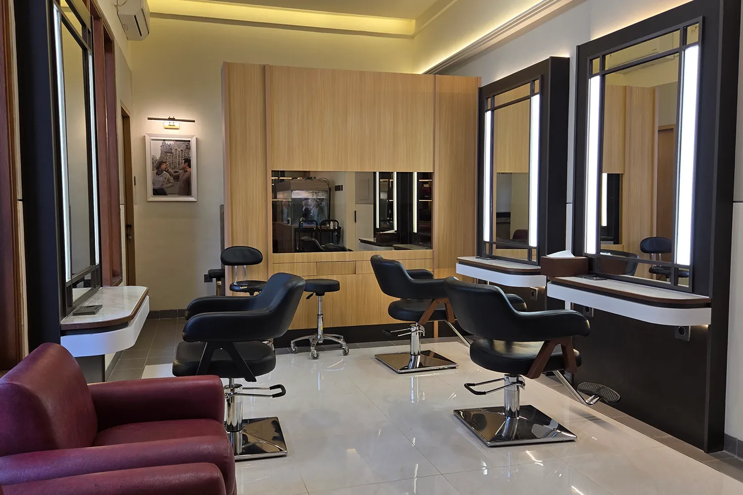 Inside Ganda Hair Studio: three black styling chairs, lit mirrors and warm wood panels